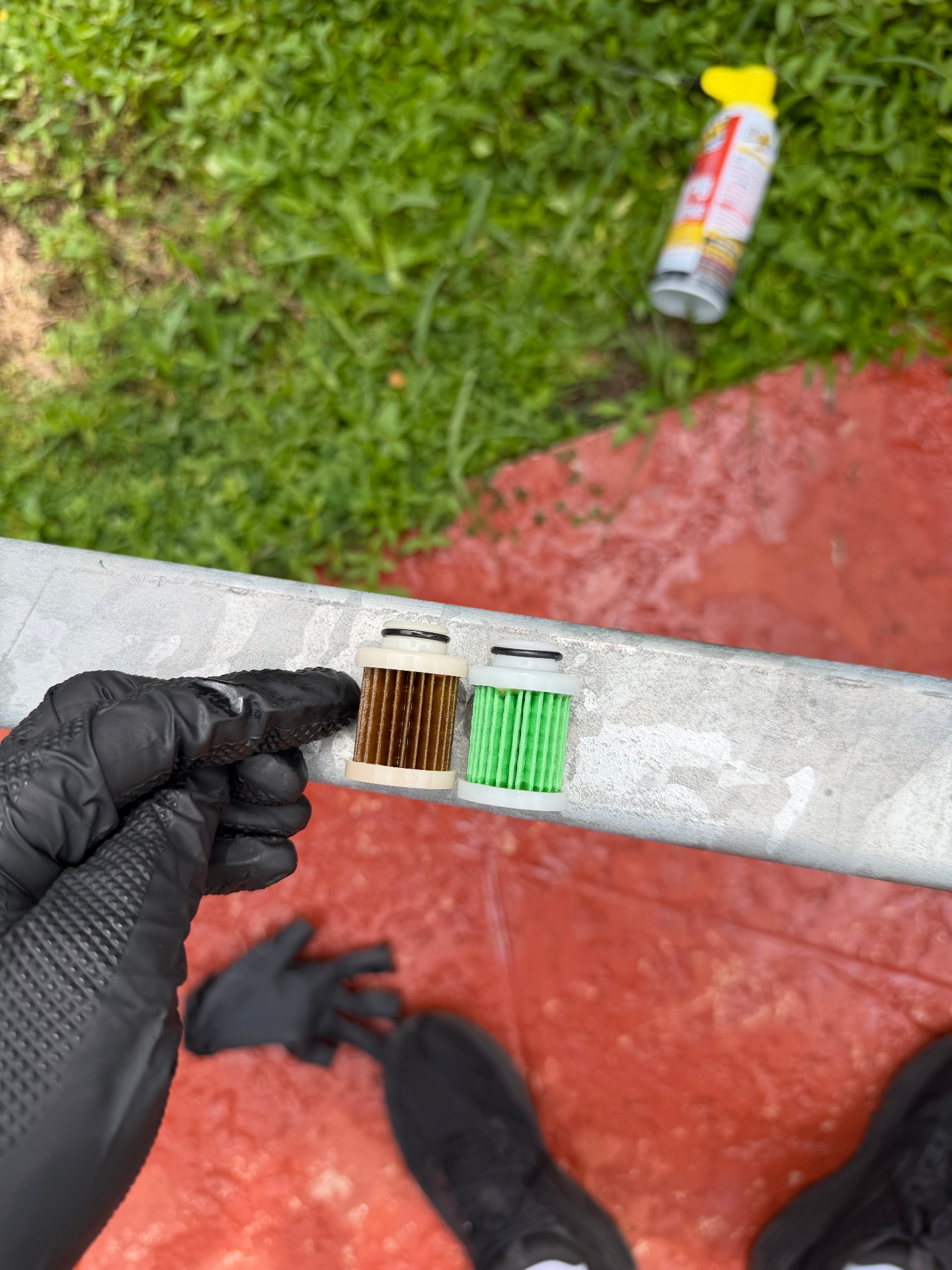 Dark brown clogged fuel filter element beside a clean green replacement element